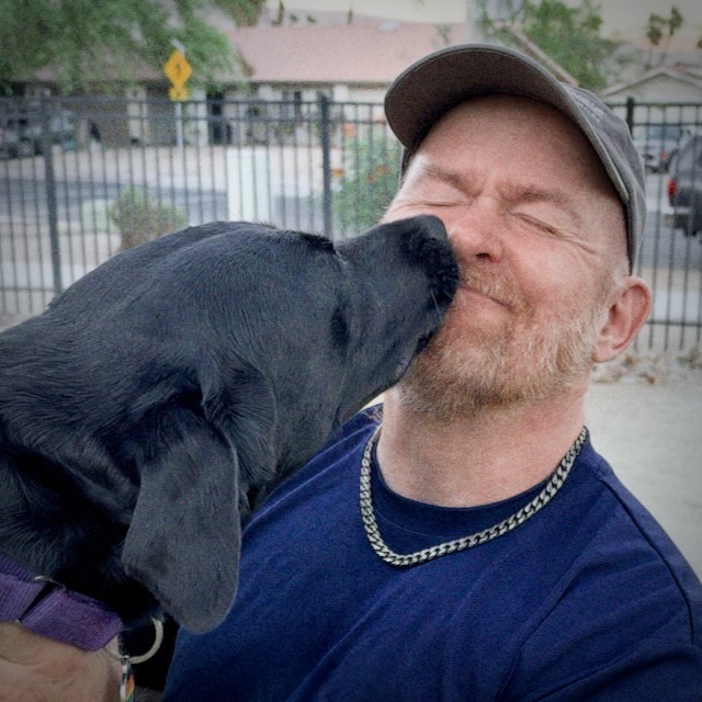 Philly, a black Labrador, gives Ron a kiss on the cheek.